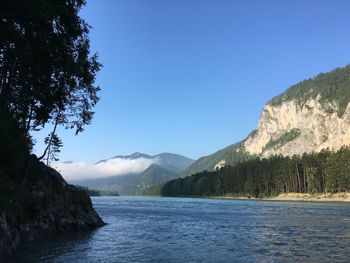 Scenic view of river and mountains against clear blue sky