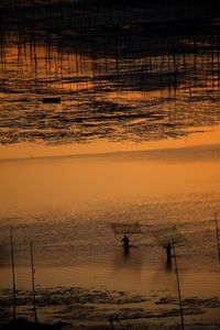 Silhouette man working at beach during sunset