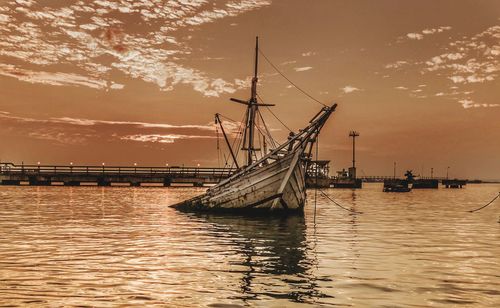 Sailboats in sea against sky during sunset