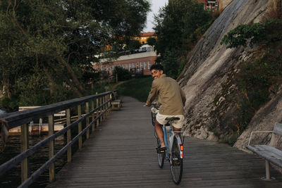 Happy young man looking over shoulder while cycling on pier