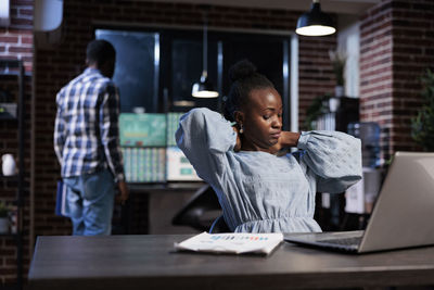 Young woman using laptop while sitting on table