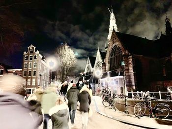 Rear view of people walking on street in city at night