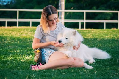 Young woman with dog sitting on grass