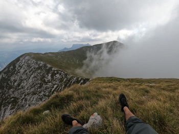 Low section of people on mountain against sky