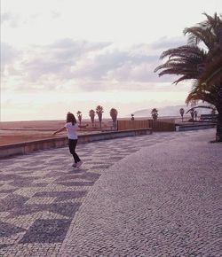 Rear view of woman walking on shore against sky