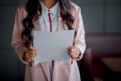 Midsection of woman holding paper