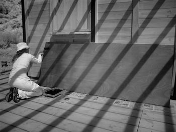 Rear view of woman kneeling while roller on wooden sheet