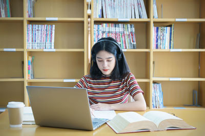 Young woman reading book on table