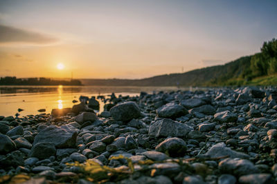 Rocks on beach against sky during sunset