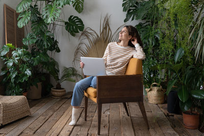 Dreamy woman rest after finished work on laptop look in window sitting in chair at cozy home garden