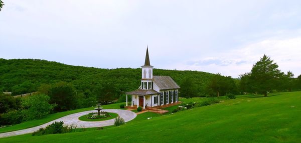 Built structure by trees and building against sky