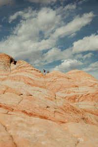 Hiker and dog walk in crux of petrified sand dunes on desert horizon