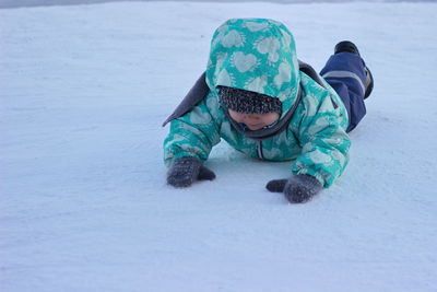 Full length of child lying on snow covered land