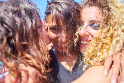 Close-up of friends embracing in sunny day