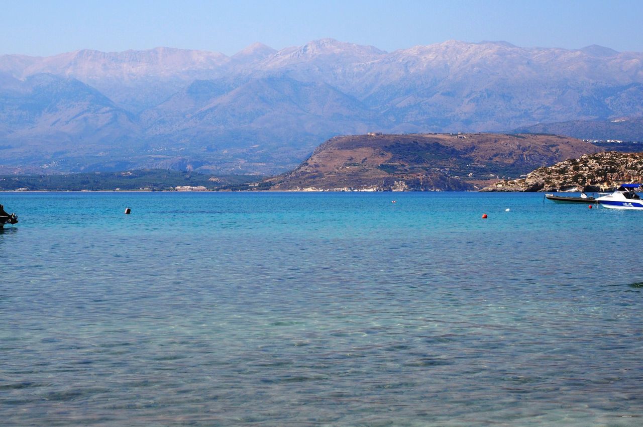 water, mountain, sea, nautical vessel, scenics, transportation, boat, tranquil scene, tranquility, mountain range, beauty in nature, waterfront, nature, mode of transport, incidental people, beach, sky, blue, clear sky, coastline