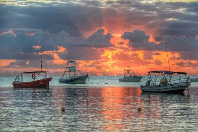 Sailboat sailing in sea against cloudy sky at sunset