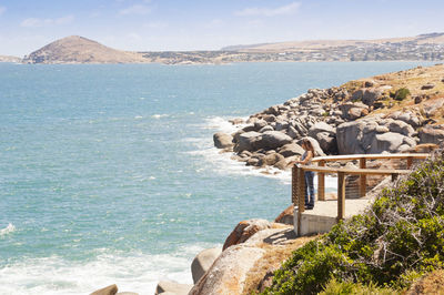 Young female tourist along the edge of granite island, south australia, near victor harbour.