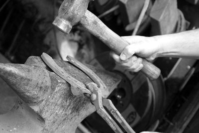 Cropped image of blacksmith hammering horseshoe on anvil