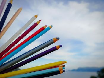 Close-up of colored pencils against sky