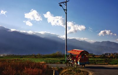 Horse cart on road by mountains against sky