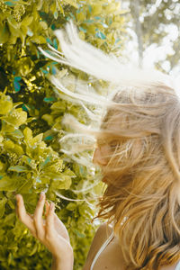 Woman with tousled hair against tree