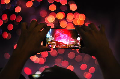 Close-up of person photographing fireworks at night