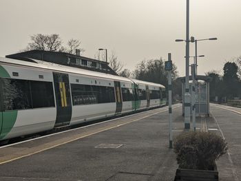 Train at railroad station in city against sky