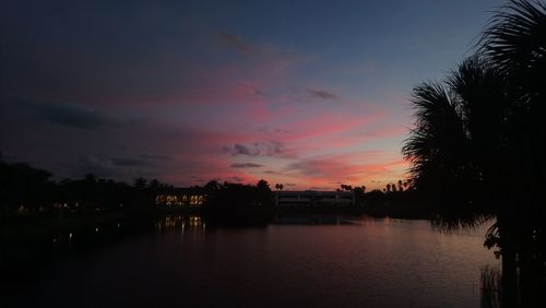 Silhouette trees by lake against romantic sky at sunset