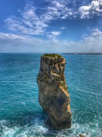 Rock formation by sea against blue sky