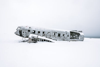 Abandoned airplane on snow covered landscape against clear sky