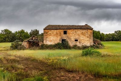 Abandoned house on field against sky