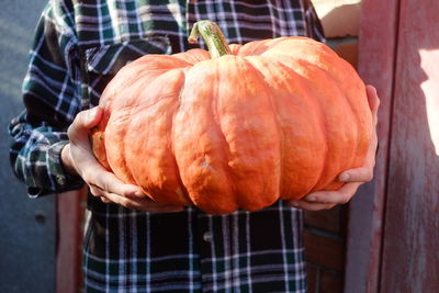 Midsection of person holding pumpkin