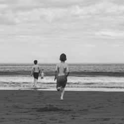 Three children running towards the sea.