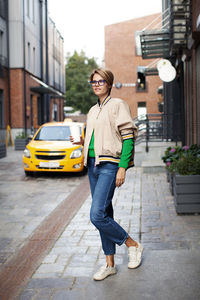 Female model short hair drinking coffee and waiting for taxi. outfit trend street style fashion