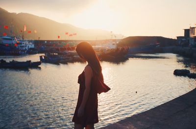 Woman standing in river during sunset