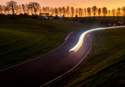 Aerial view of road amidst trees against sky during sunset