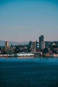 Buildings by sea against clear sky