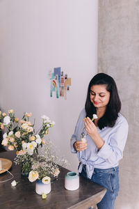 Young woman using scissors while standing on table