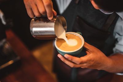 Midsection of barista preparing coffee in cafe