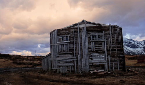 Old hut on field against sky during sunset