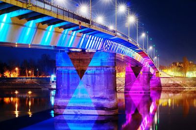 Illuminated bridge against blue sky at night