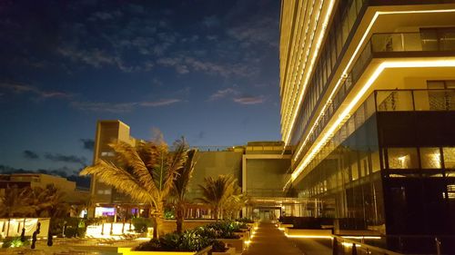 Illuminated street amidst buildings in city at night