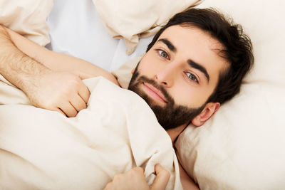 Portrait of young man lying on bed at home