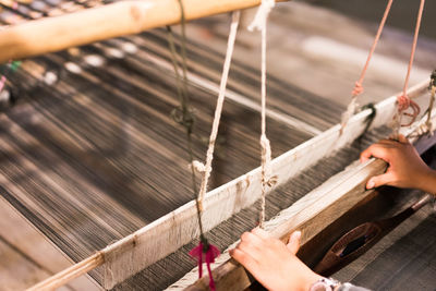 Cropped hands of person holding loom while working in textile industry