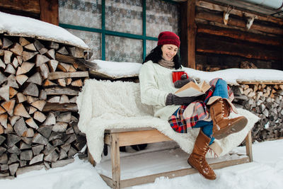 Woman in warm clothing reading book sitting on bench