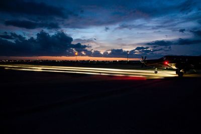 Light trails on road against sky at sunset