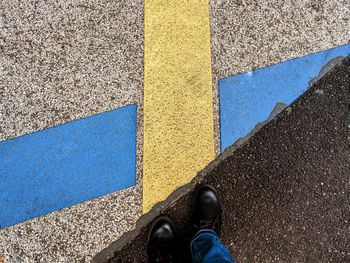 Everyday solidarity, standing in front of road markings crosswd blue and yellow lines