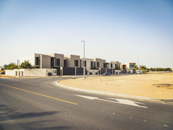 Empty road by buildings against sky in city