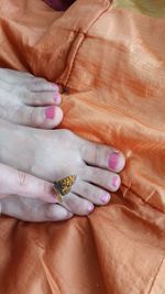 Low section of woman with butterfly on orange textile