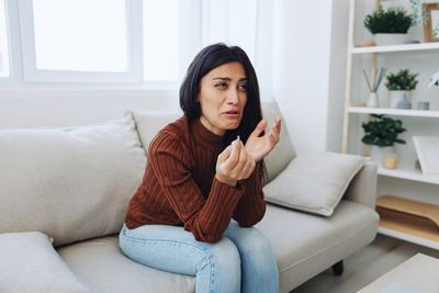 Young woman using mobile phone while sitting on sofa at home